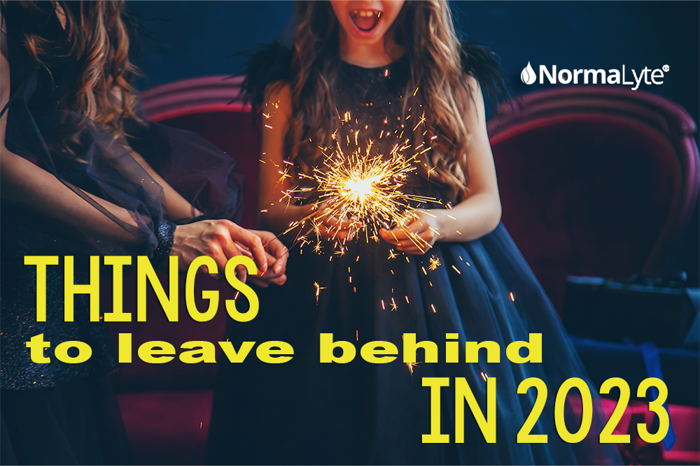 Two girls holding a gold sparkler on new years.  Caption reads Things to Leave Behind in 2023. NormaLyte logo in background