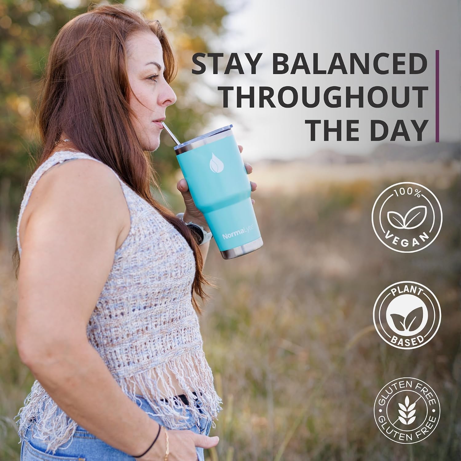 A woman outdoors drinking from a light blue vegan tumbler with a straw. The image includes text reading 'STAY BALANCED THROUGHOUT THE DAY' and badges stating '100% VEGAN', 'PLANT BASED', and 'GLUTEN FREE'.
