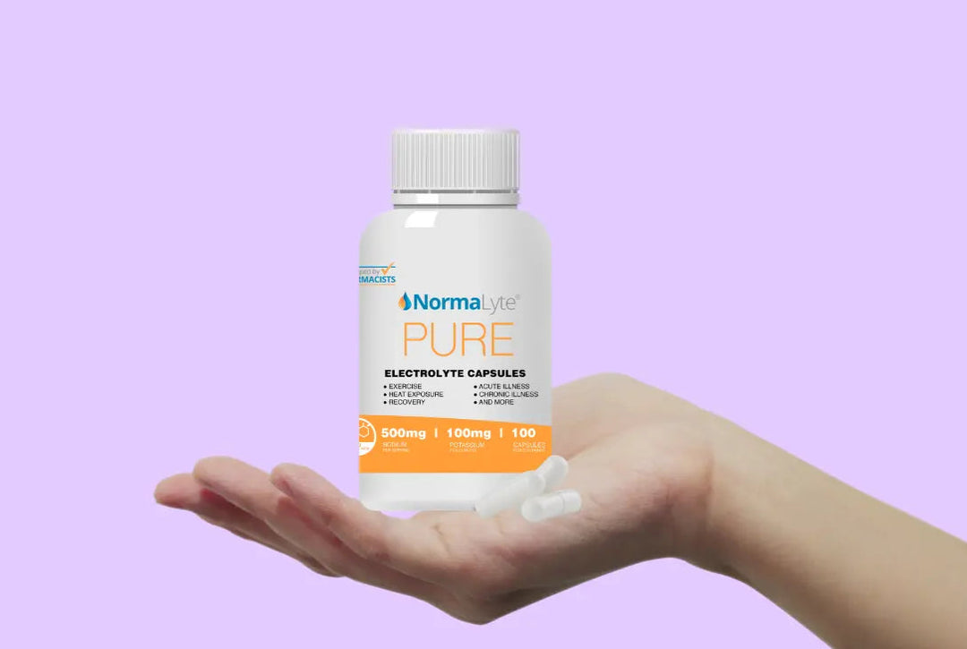 Bottle of NormaLyte Pure electrolyte capsules held in a hand against a purple background