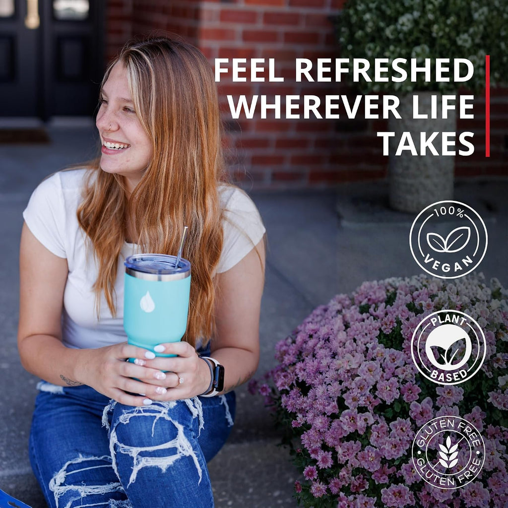 A smiling woman sits outdoors holding a light blue insulated tumbler with a straw. Large text reads 'FEEL REFRESHED WHEREVER LIFE TAKES,' and circular badges on the right say '100% Vegan,' 'Plant Based,' and 'Gluten Free.