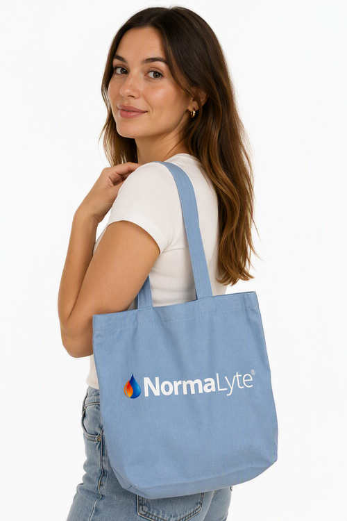 Woman carrying a light blue NormaLyte canvas everyday tote bag over her shoulder.