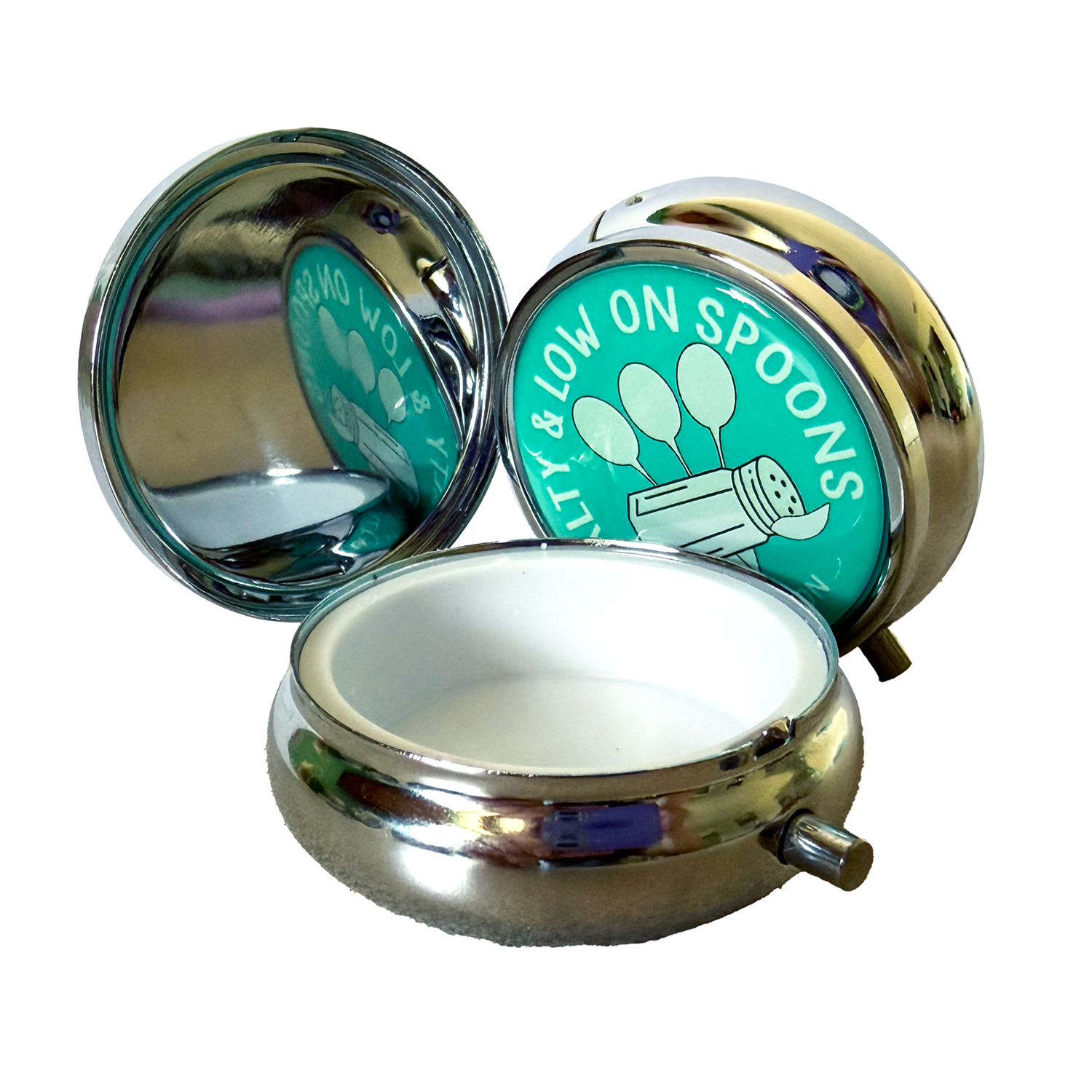 Open NormaLyte Salty & Low on Spoons metal pill tin showing an interior mirror and a teal graphic featuring a salt shaker and three spoons